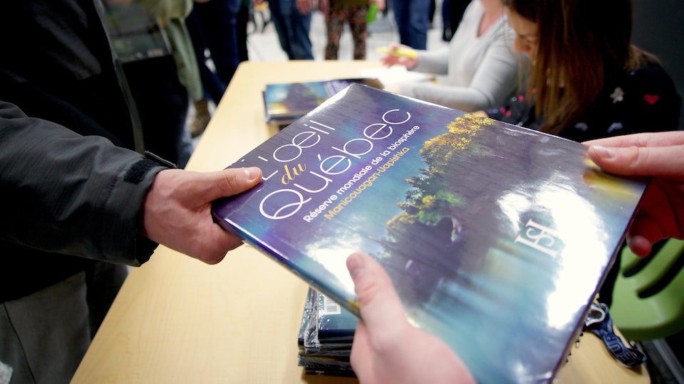 Un étudiant du Cégep de Baie-Comeau reçoit une copie du livre L'oeil du Québec.