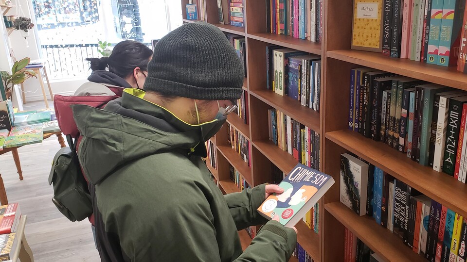 un lecteur regarde un livre dans une librairie.