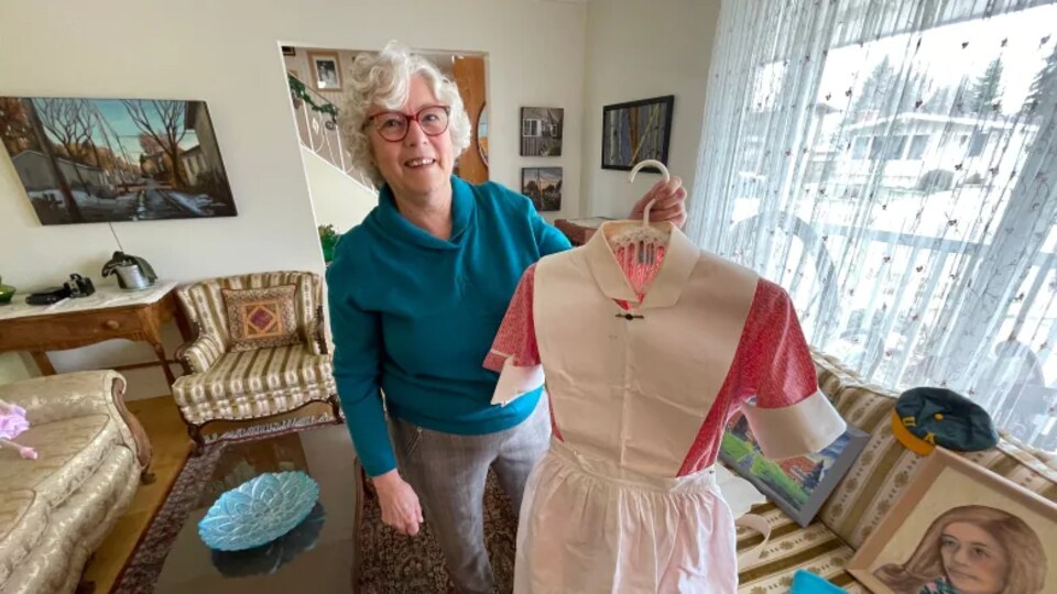 Une femme montre son uniforme d'infirmière.