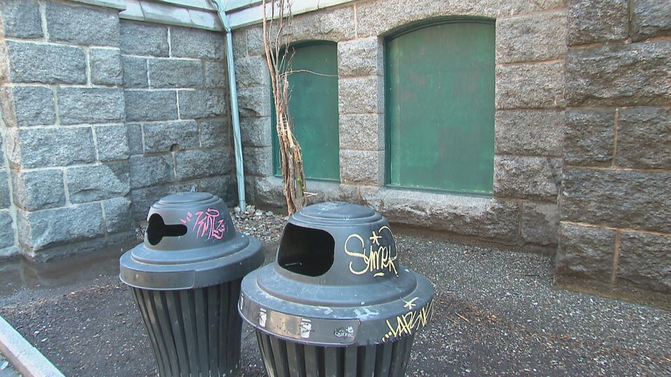 Deux poubelles de rues couvertes de graffitis. 