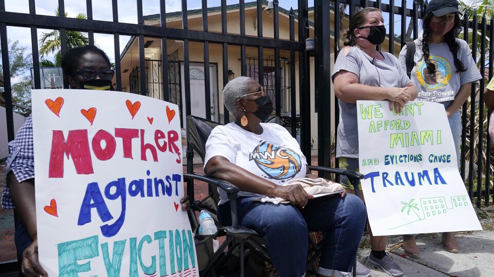 Quatre femmes avec deux affiches devant un complexe locatif en Floride.