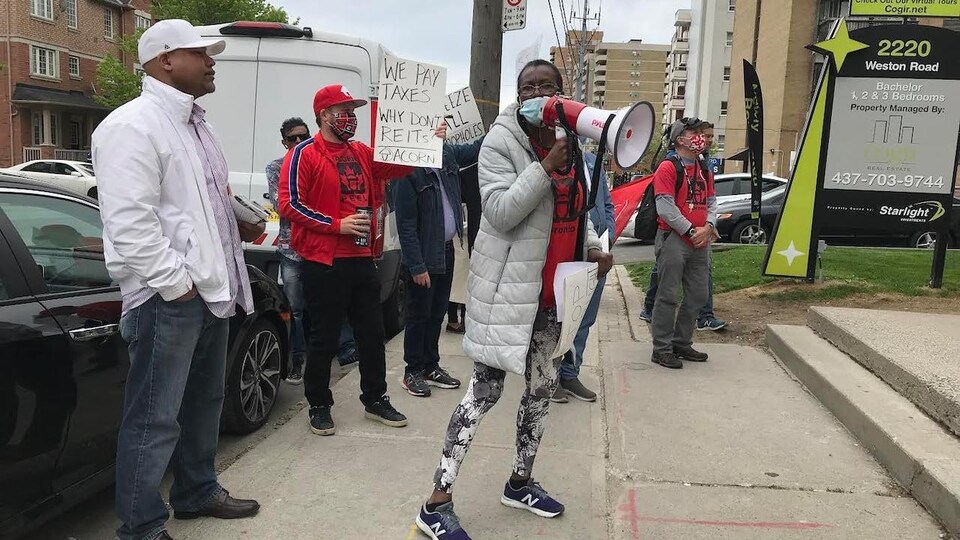 Marcia Stone tient un porte-voix pendant une manifestation devant un immeuble.