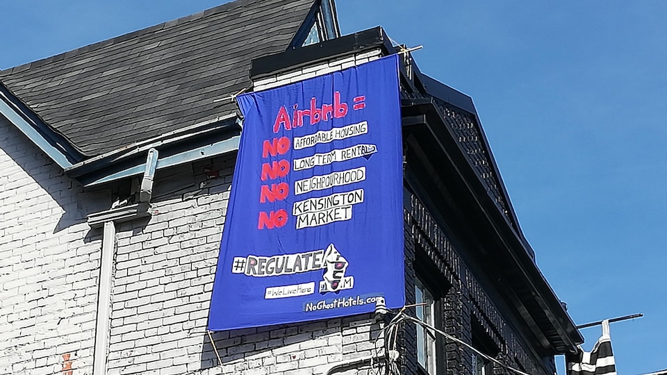 Une affiche porte un message contre AirBnb sur une maison dans Kensington Market.