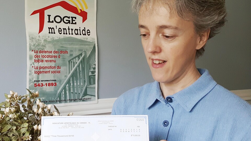 Sonia Côté tient le chèque envoyé parle Vatican.