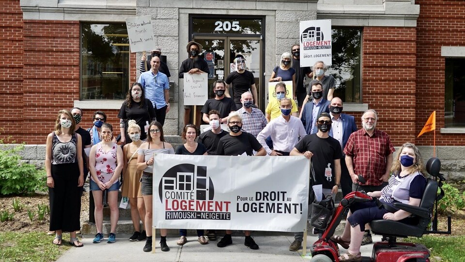 Des manifestants tiennent une banderole où l'on peut lire : pour le droit au logement!