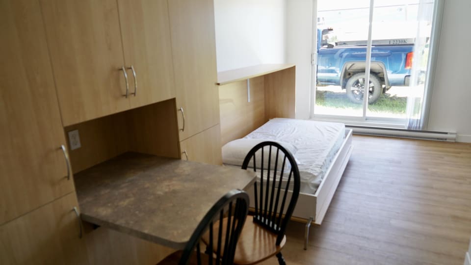 Un logement d'urgence qui comporte un lit et une petite table.                               