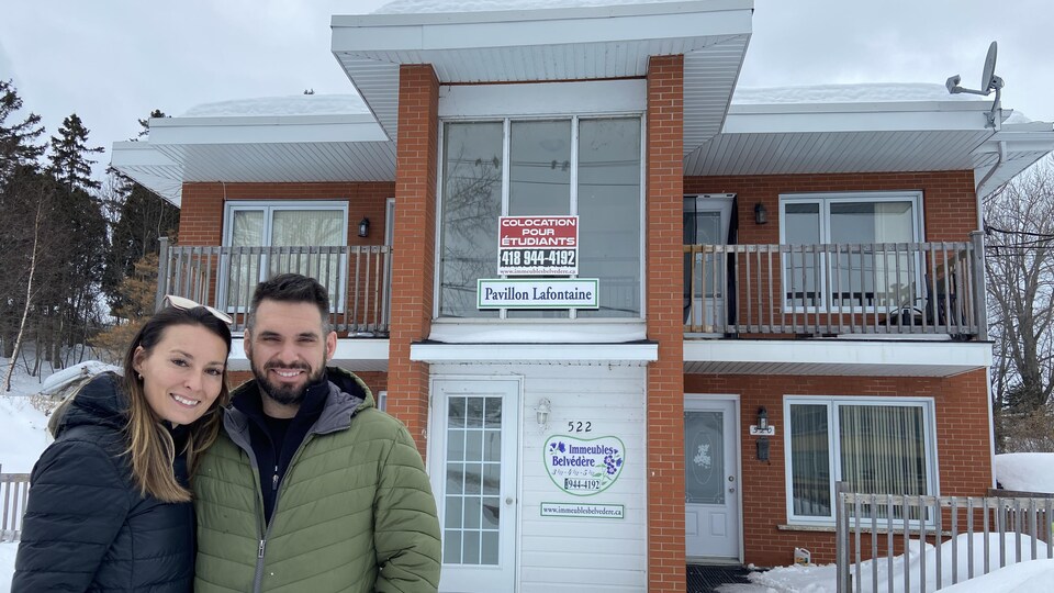 Le couple devant un immeuble à logements. 