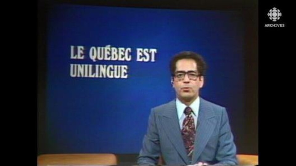 Le présentateur Paul-Émile Tremblay anime le Téléjournal; à l'arrière, l'inscription « Le Québec est unilingue ».