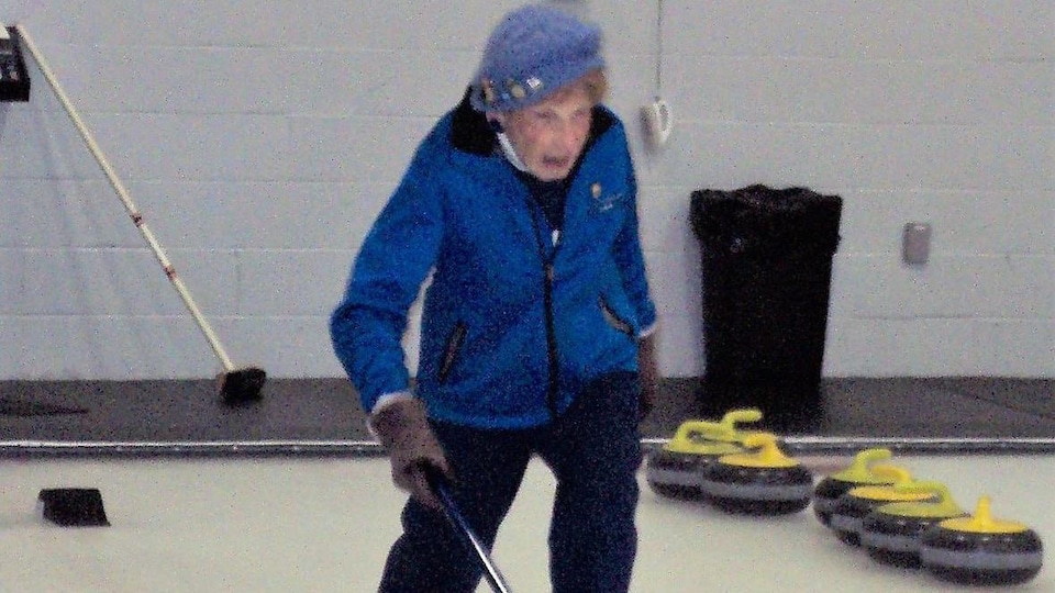 Une femme âgée qui joue au curling.