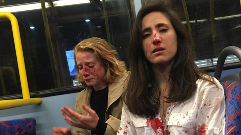 Melania Geymonat, le nez en sang et la chemise tachée de sang, avec son amie, le visage ensanglanté dans un autobus.