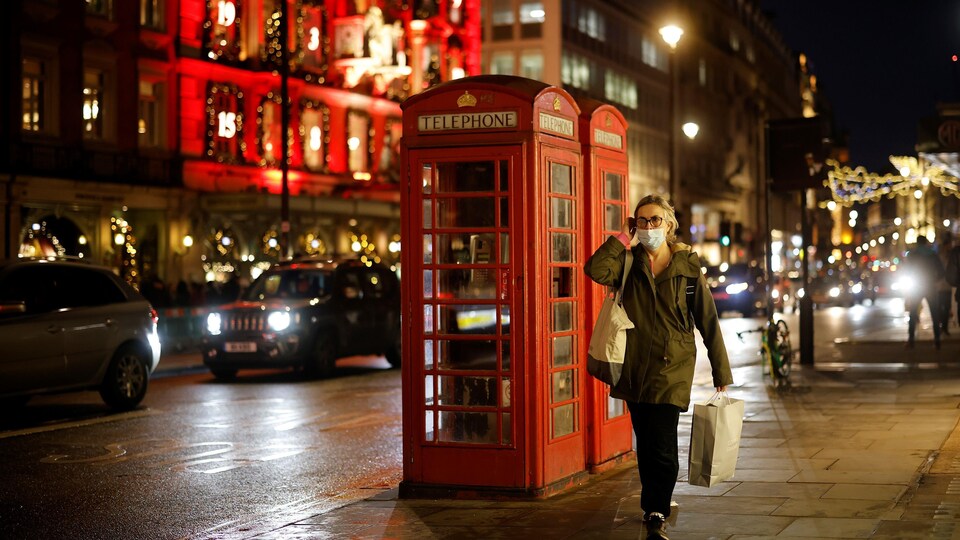 Une piétonne portant un masque de protection passe devant les cabines téléphoniques rouges à Londres le 19 décembre 2020.