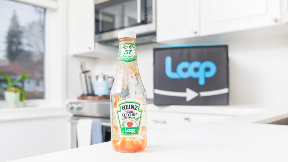 Une bouteille de ketchup vide sur le comptoir d'une cuisine, devant un sac de Loop.