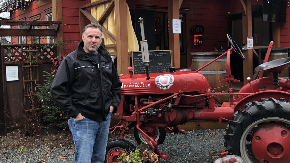 Loren Taves à côté d'un ancien tracteur, devant une cidrerie.