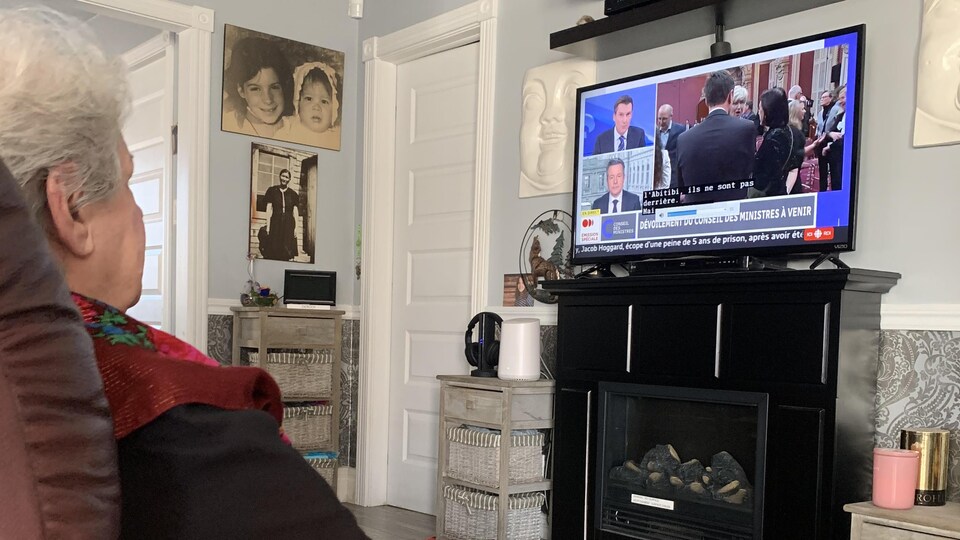 Une femme assise devant la télévision. 