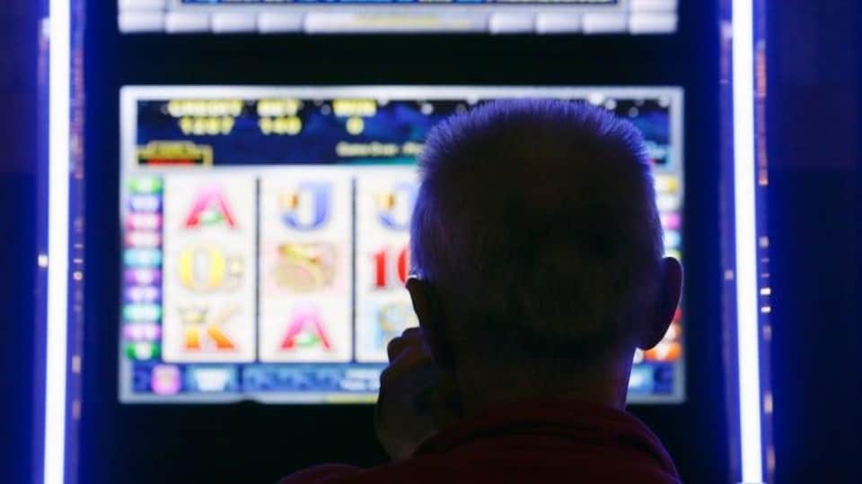 Une homme regarde un terminal de loterie vidéo.