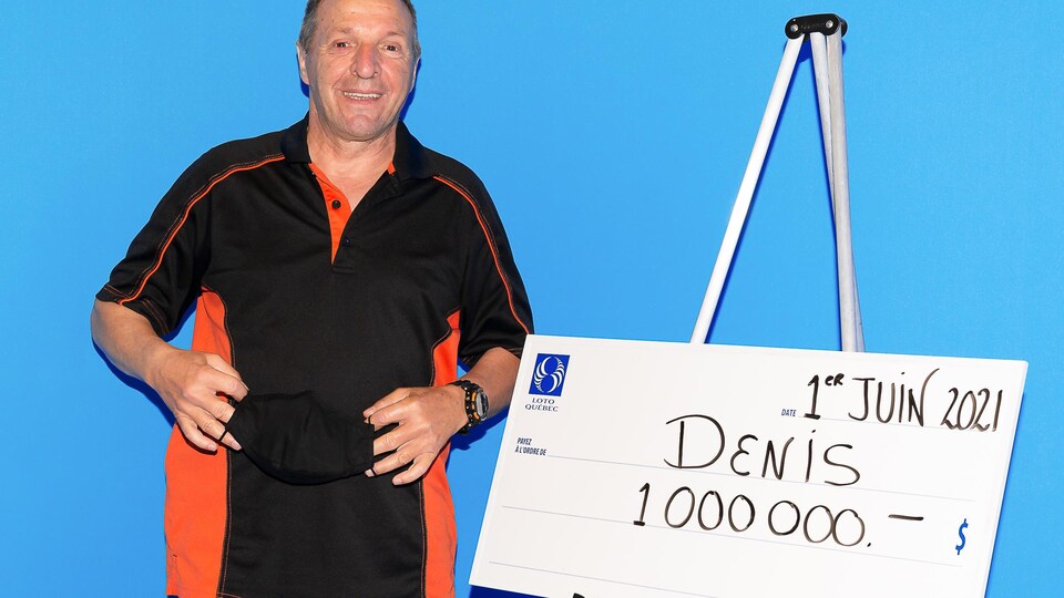 Denis Gagné sourit devant un chèque d'un million de dollars.