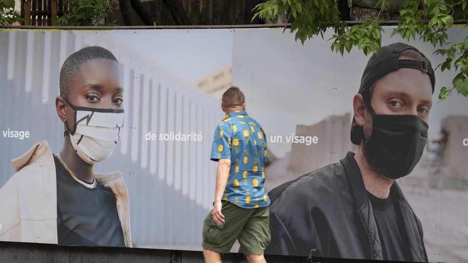 Un homme passe devant un panneau publicitaire sur lequel apparaît Loud et une autre personne portant un couvre-visage.