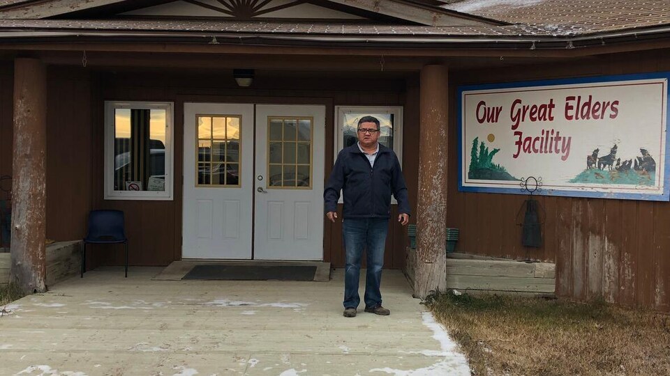 Un homme se tient devant un bâtiment.