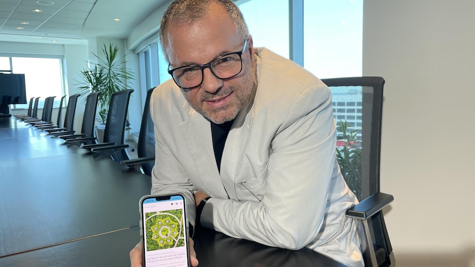 Portrait d'un homme assis à une table de réunion dans un bureau. Il se penche en avant vers l'objectif de l'appareil photo.