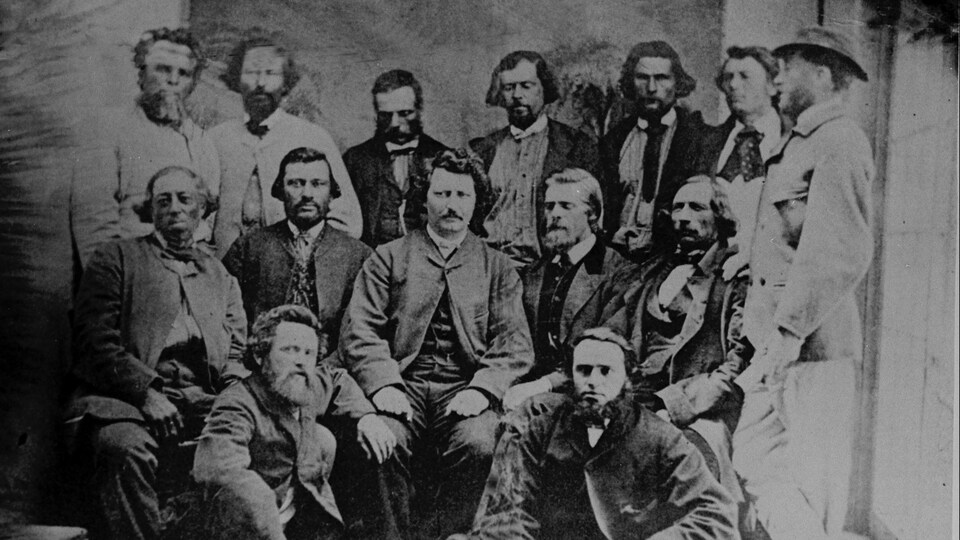 Louis Riel entouré de 13 hommes.
