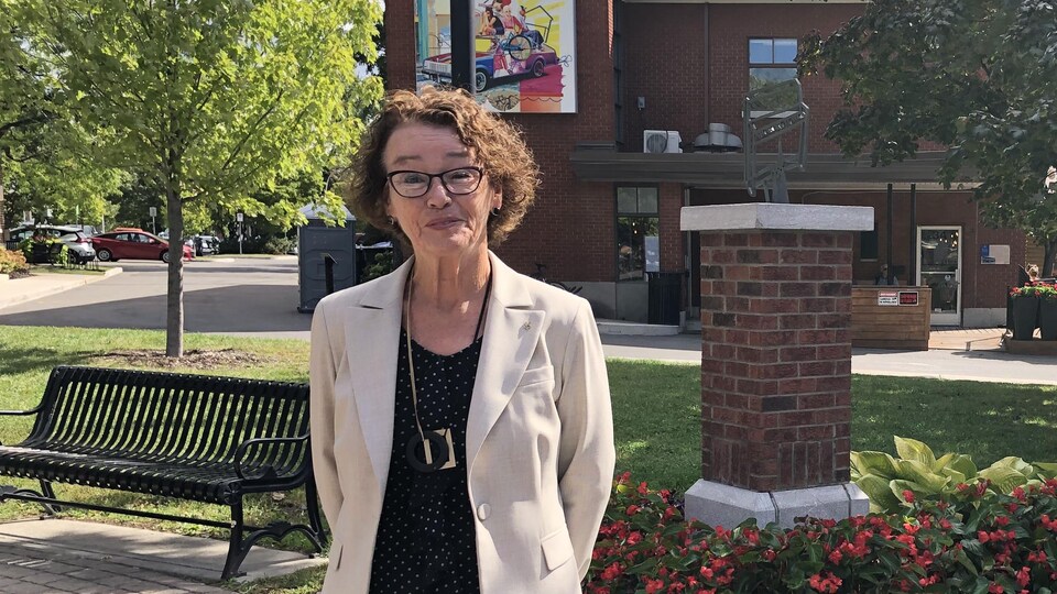 Louise Chabot debout dans un parc, devant un édifice.