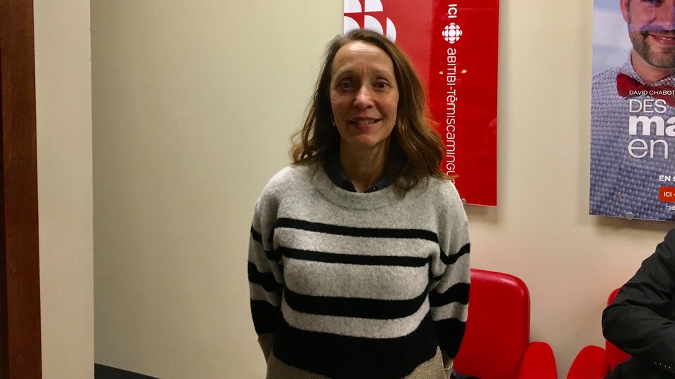 Louise Perreault devant l'affiche d'ICI Abitibi-Témiscamingue dans la station à Rouyn-Noranda.