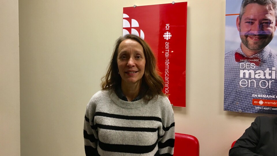 Louise Perreault devant l'affiche d'ICI Abitibi-Témiscamingue dans la station à Rouyn-Noranda.