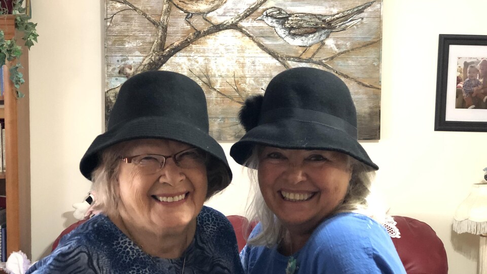 Deux femmes avec un chapeau qui sourient.