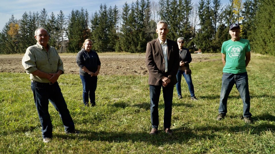 Luc Trudel est dans un champ en compagnie de quatre propriétaires de terrains.