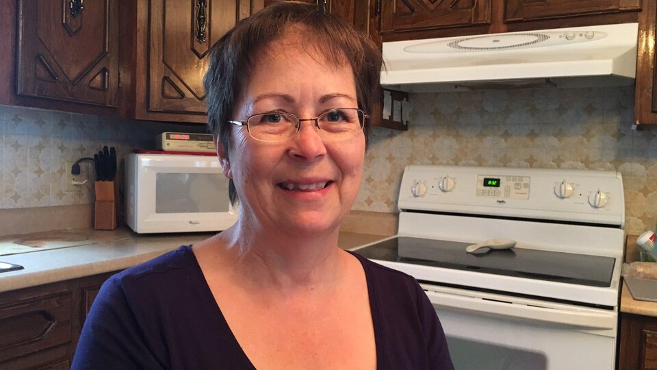 Une dame souriante assise dans sa cuisine