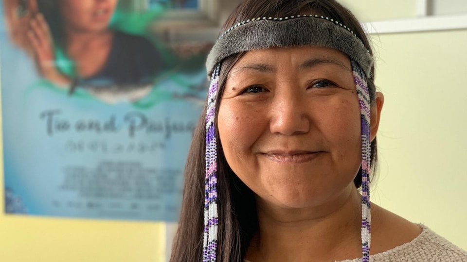 Lucy Tulugarjuk sourit et pose pour la photo avec un bandeau traditionnel.
