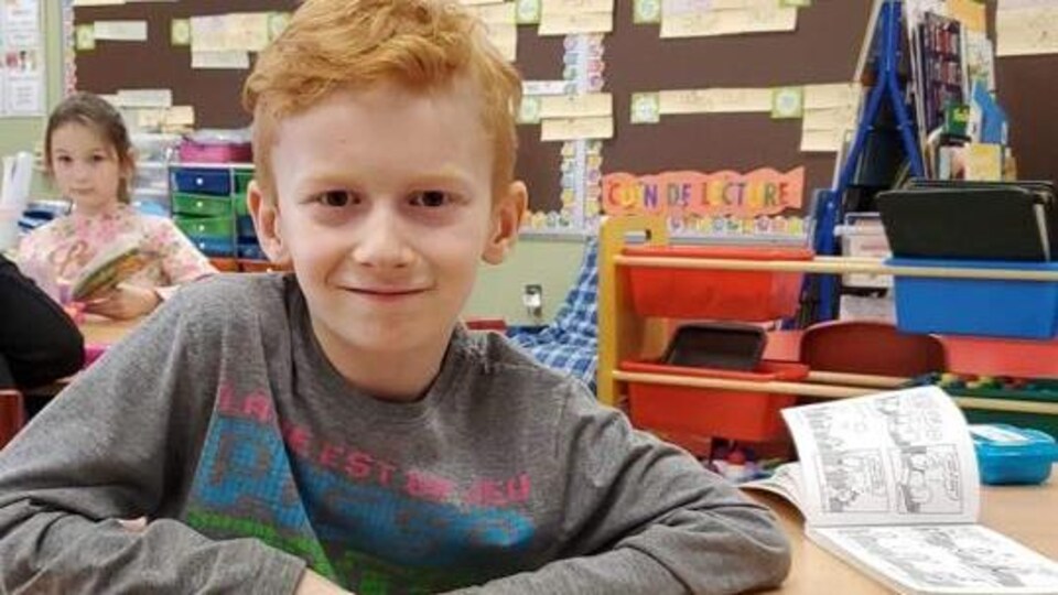 Un enfant de deuxième année dans sa classe regardant la caméra.