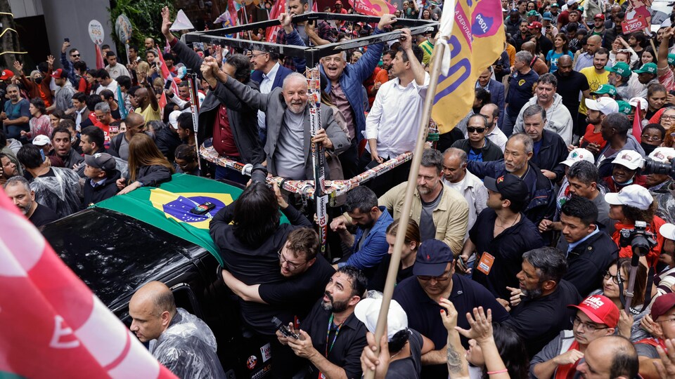 À l'arrière d'une camionnette, Lula lève le bras au milieu d'une foule dense.