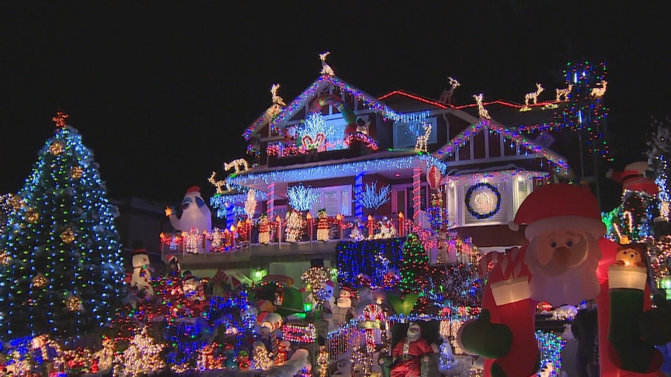 Une maison et son jardin décorés de nombreuses lumières de Noël et d'un sapin illuminé à North Vancouver.