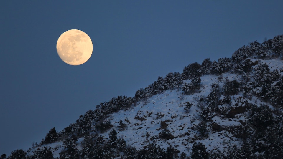 La Lune presque pleine est vue derrière une montagne en Corse.