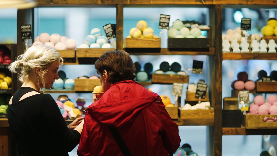 Deux femmes font face à une étagère pleine de savons multicolores.