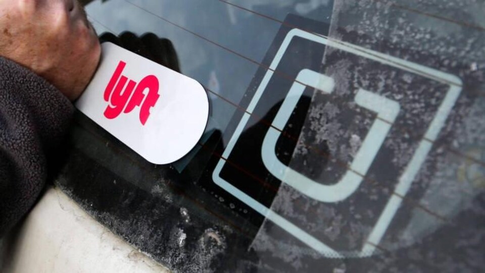 Les logos de Lyft et d'Uber sur le pare-brise d'un véhicule. 