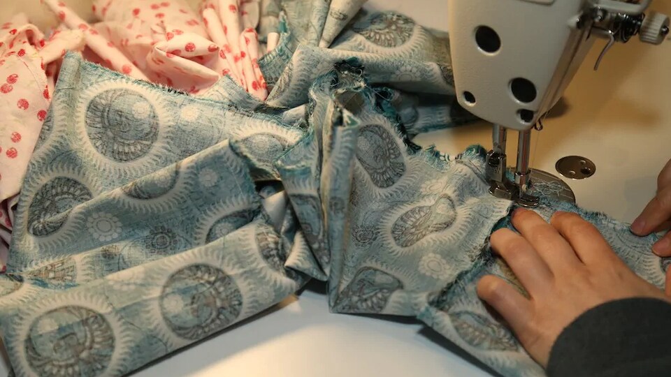 Gros plan sur un morceau de tissu en train d'être cousu dans une machine à coudre.