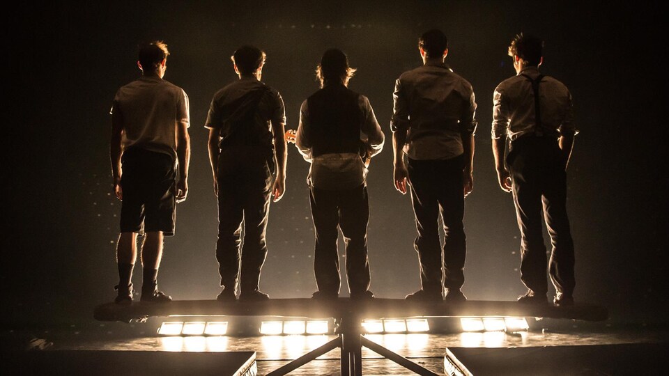 Des membres de la troupe Machine de cirque, de dos, lors d'un spectacle.