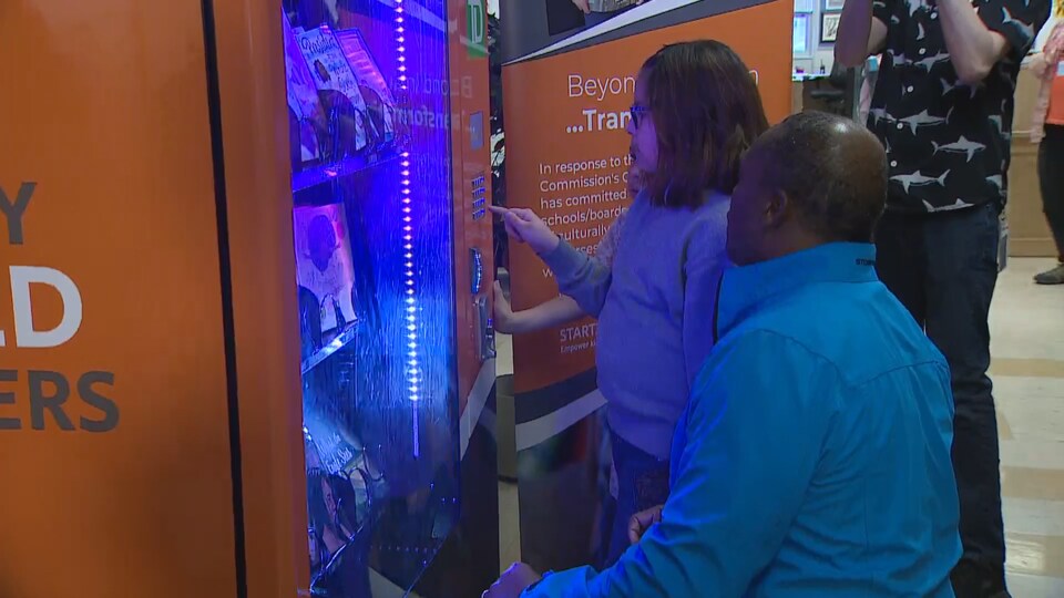 Élève qui met un jeton dans la machine distributrice de livres de l'école Catherine Nichols Gunn à Calgary.
