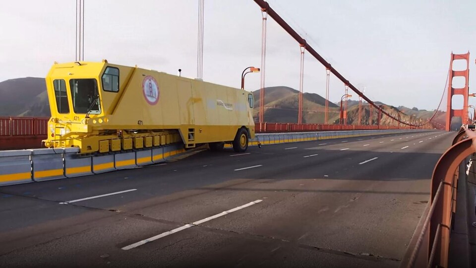 Un engin lourd de type « zipper » déplace des obstacles en béton sur le tablier du pont Golden Gate.