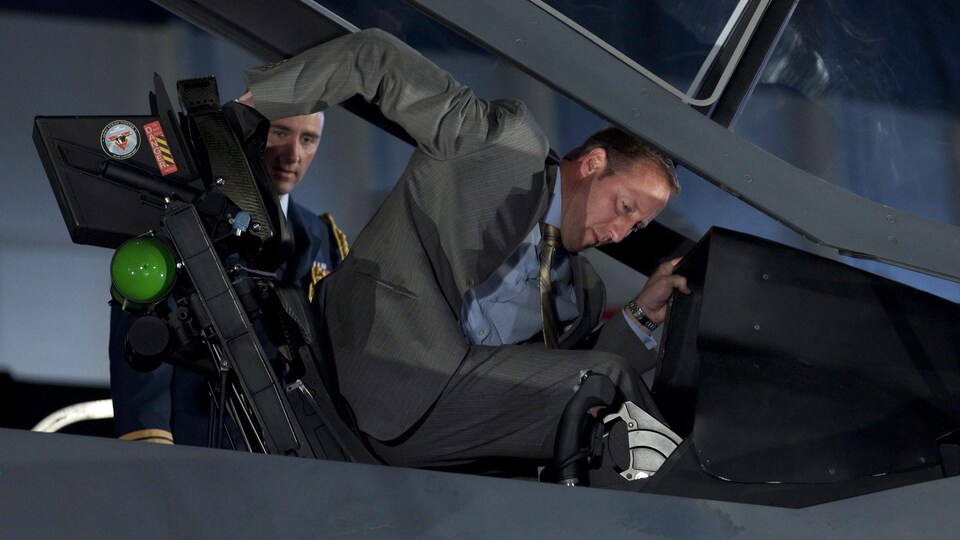 Le ministre prend place dans le cockpit d'un avion de chasse.