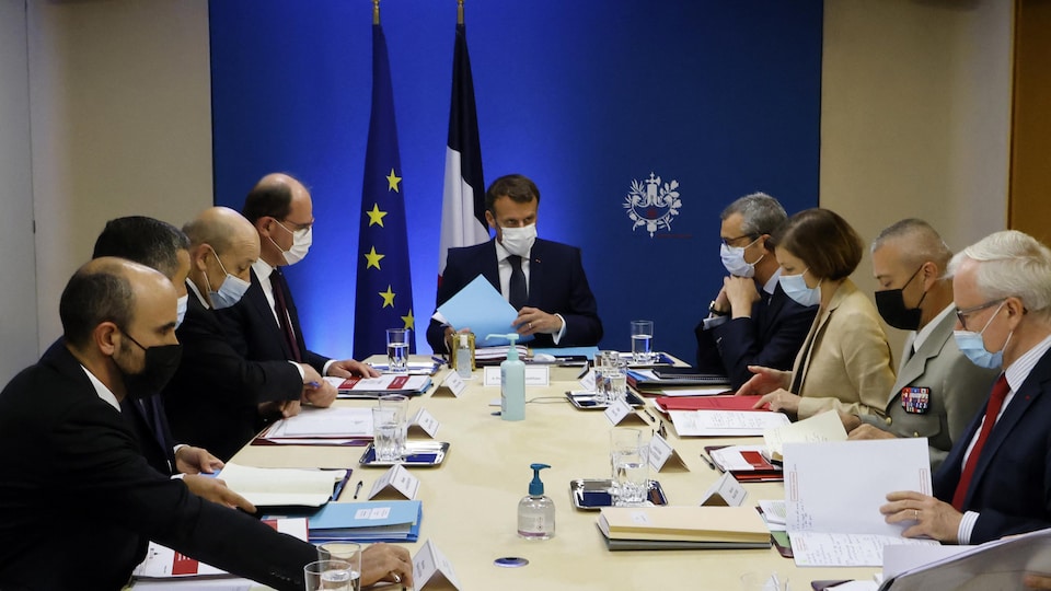 Emmanuel Macron, entouré de plusieurs personnes, autour d'une table.