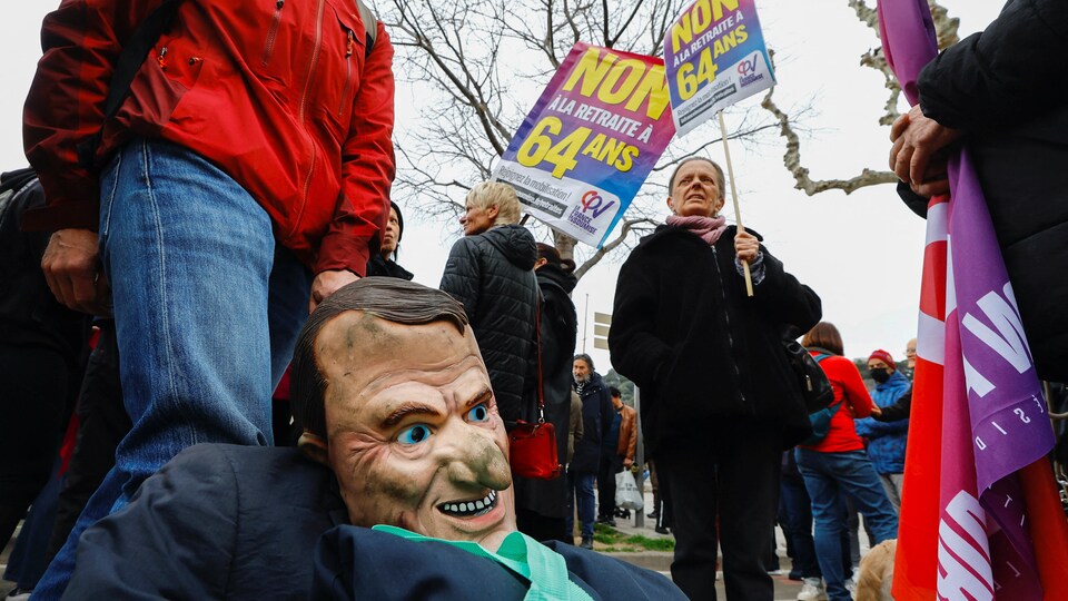 Un manifestant tient un masque à l'effigie du président français Emmanuel Macron.