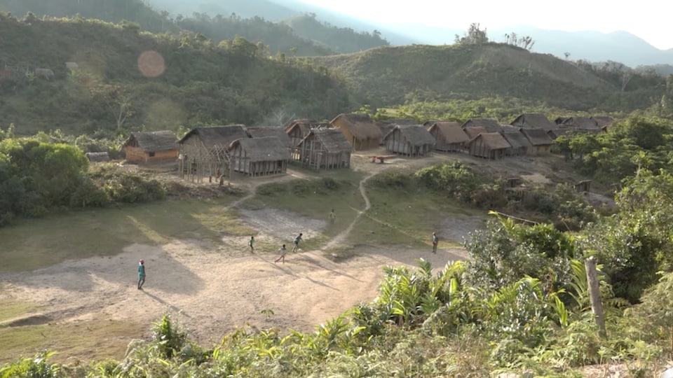 Vue aérienne d'un village de maison en bois et en pailles, construites à même la terre.