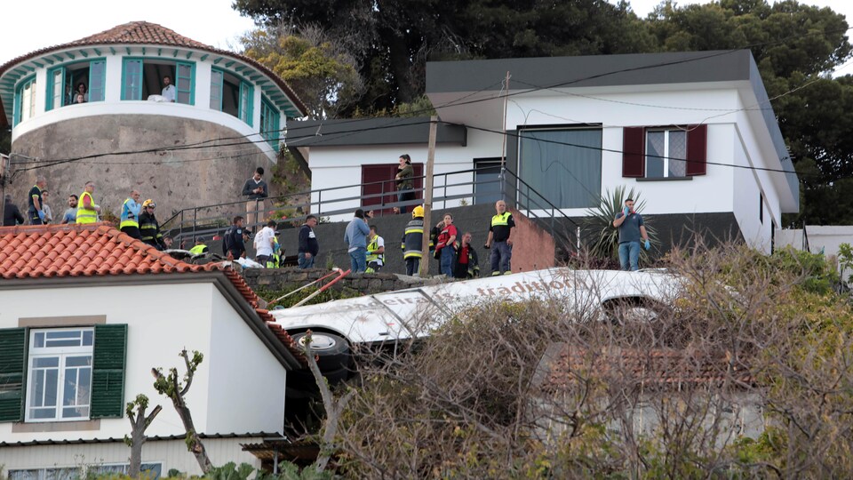 Des secouristes se tiennent à côté de l'épave d'un autocar après un accident survenu sur l'île portugaise de Madère, le 17 avril 2019. 