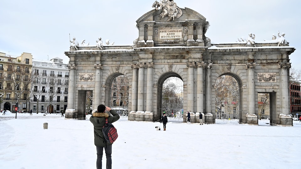 Un homme prenant une photo devant la Puerta de Alcala, à Madrid.