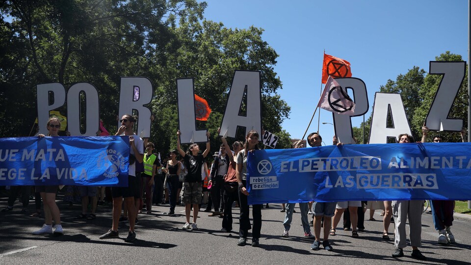 Des manifestants dans les rues de Madrid avec des pancartes qui portent la mention « pour la paix » en espagnol.