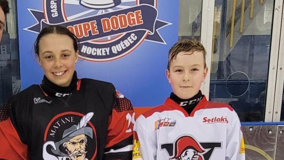 Deux enfants portant l'équipement de hockey de deux équipes différentes.