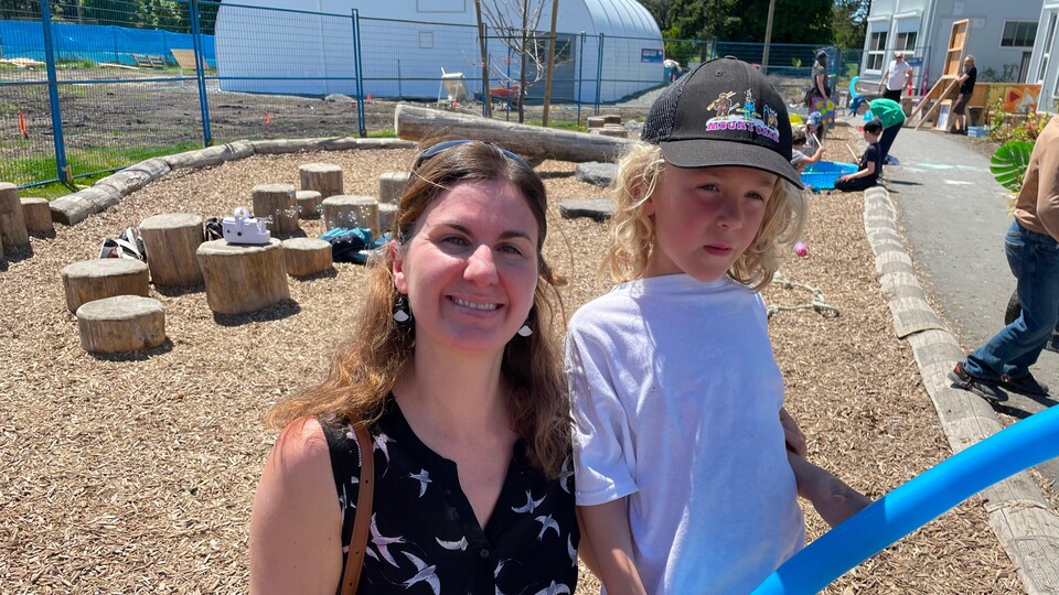 Maëva Gauthier agenouillée à côté de son enfant, devant un mini terrain de jeu, le 22 juin 2022.